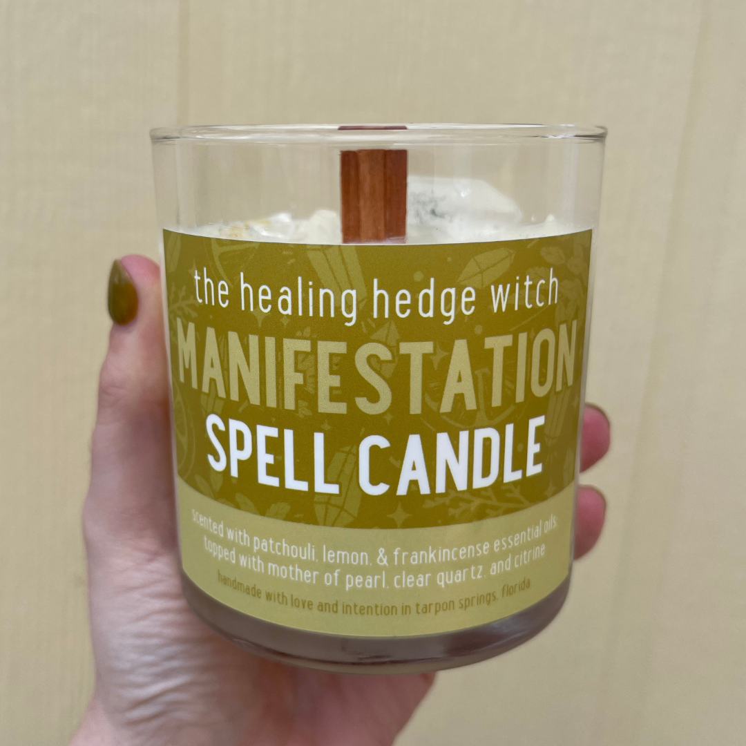 8 ounce manifestation spell candle Scented with patchouli, lemon, & frankincense essential oils; topped with mother of pearl, clear quartz, and citrine