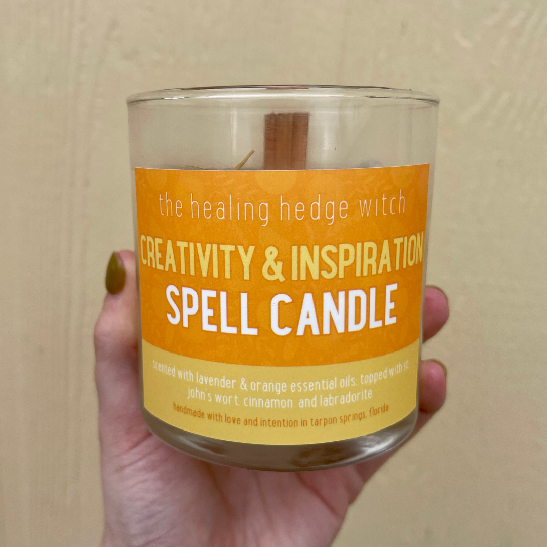 8 ounce creativity and inspiration spell candle scented with orange & lavender essential oils; topped with St. John's wort, cinnamon, & labradorite