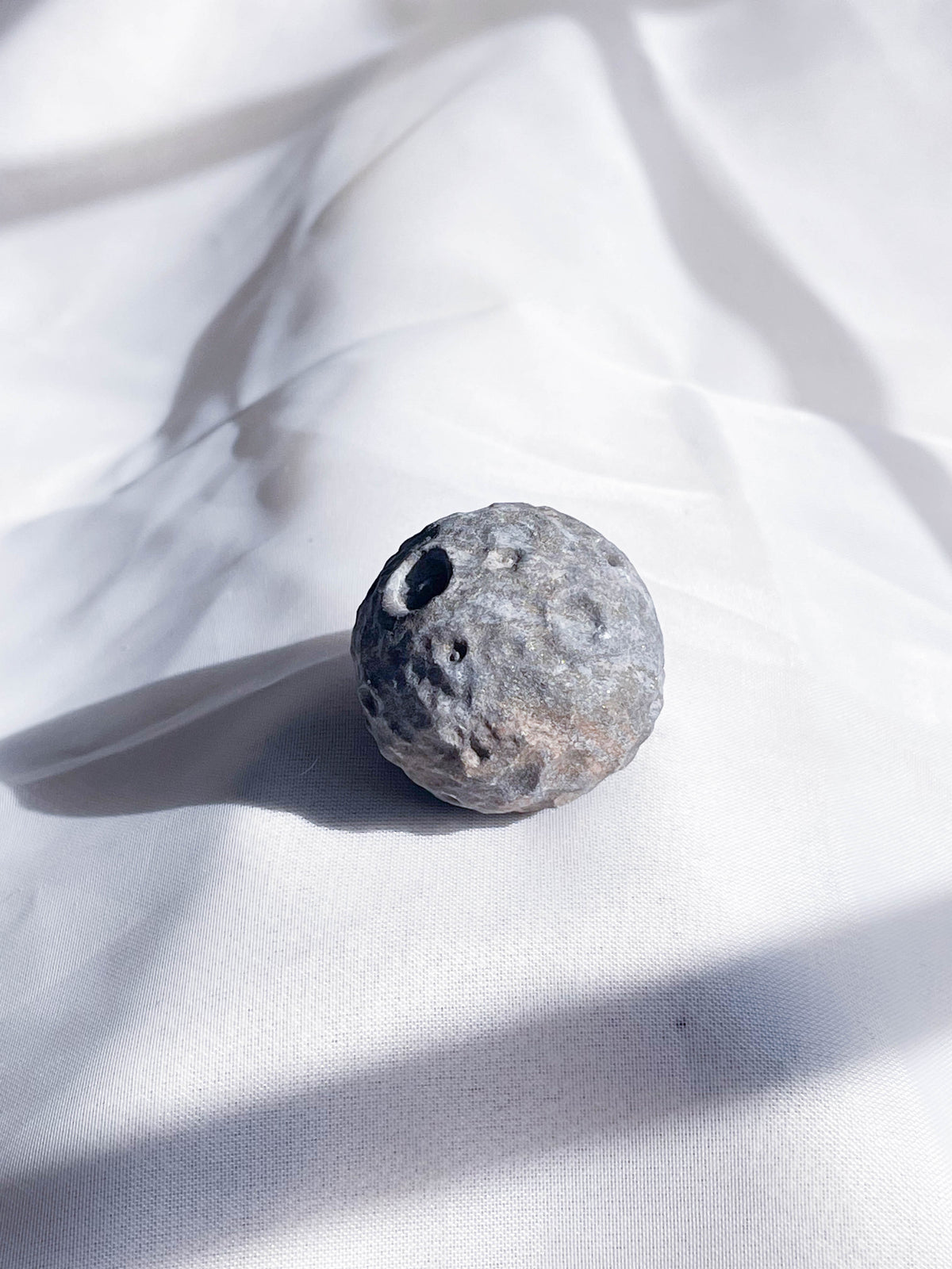 The Healing Hedge Witch’s Crater Crystal Moon is a round crystal with crater-like holes.