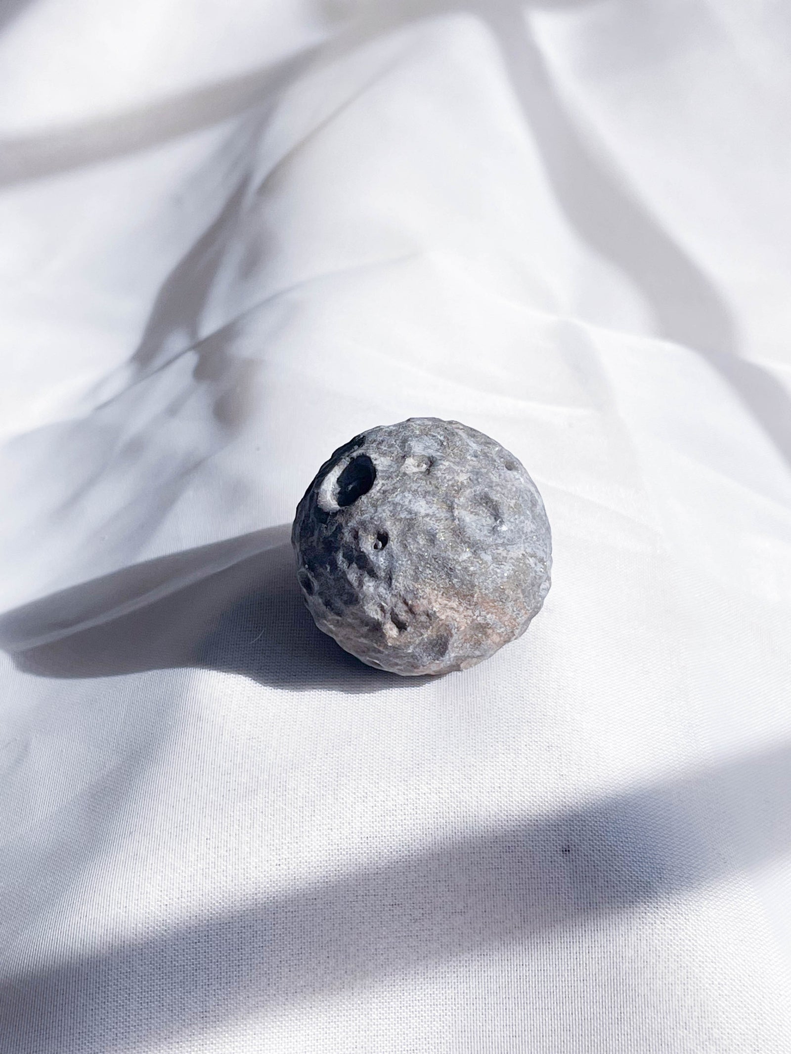 The Healing Hedge Witch’s Crater Crystal Moon is a round crystal with crater-like holes.