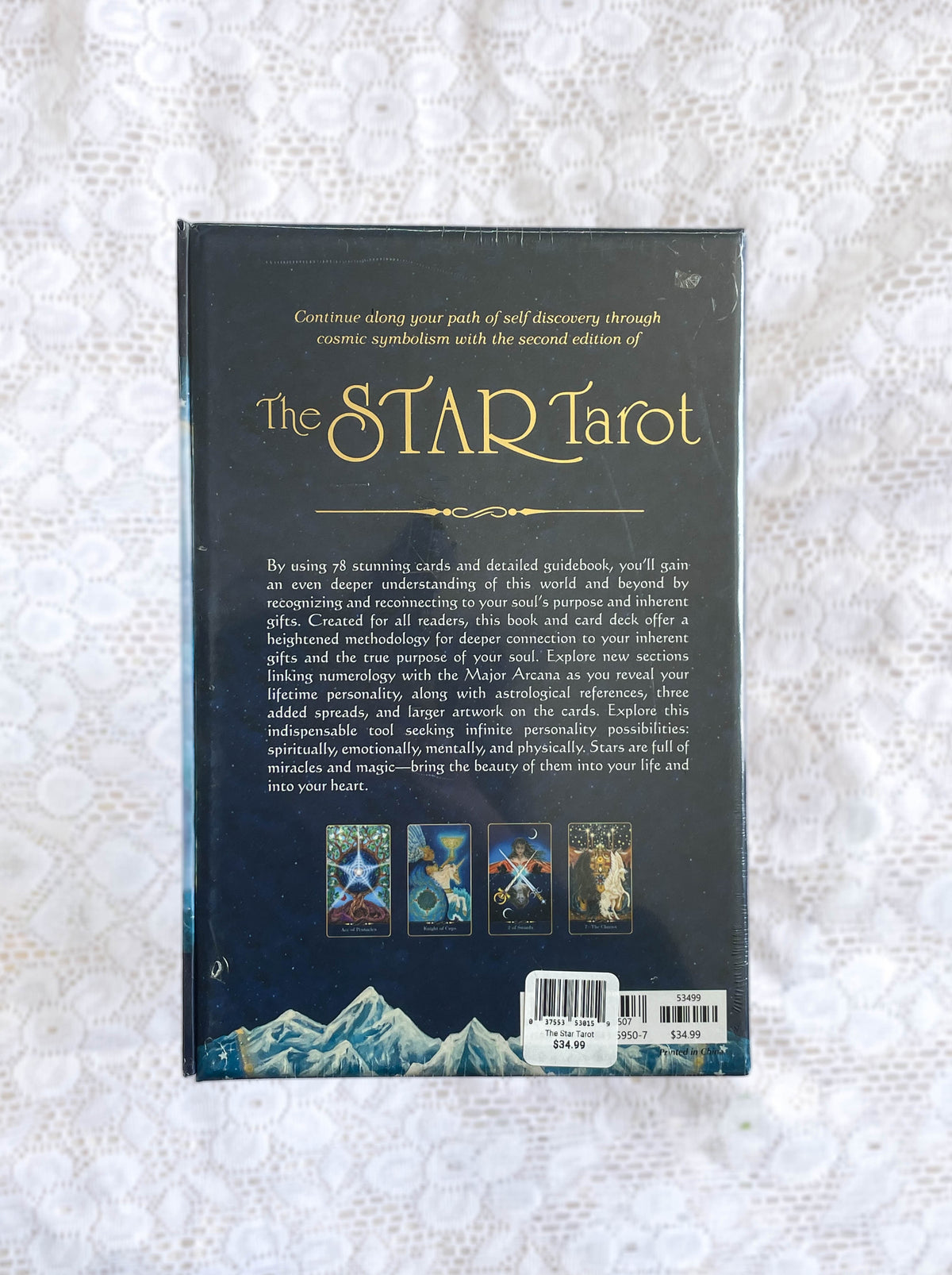 The back cover of The Star Tarot by The Healing Hedge Witch displays five tarot cards, a book summary, and mountain graphics under a starry night sky, all on a lace-patterned background.