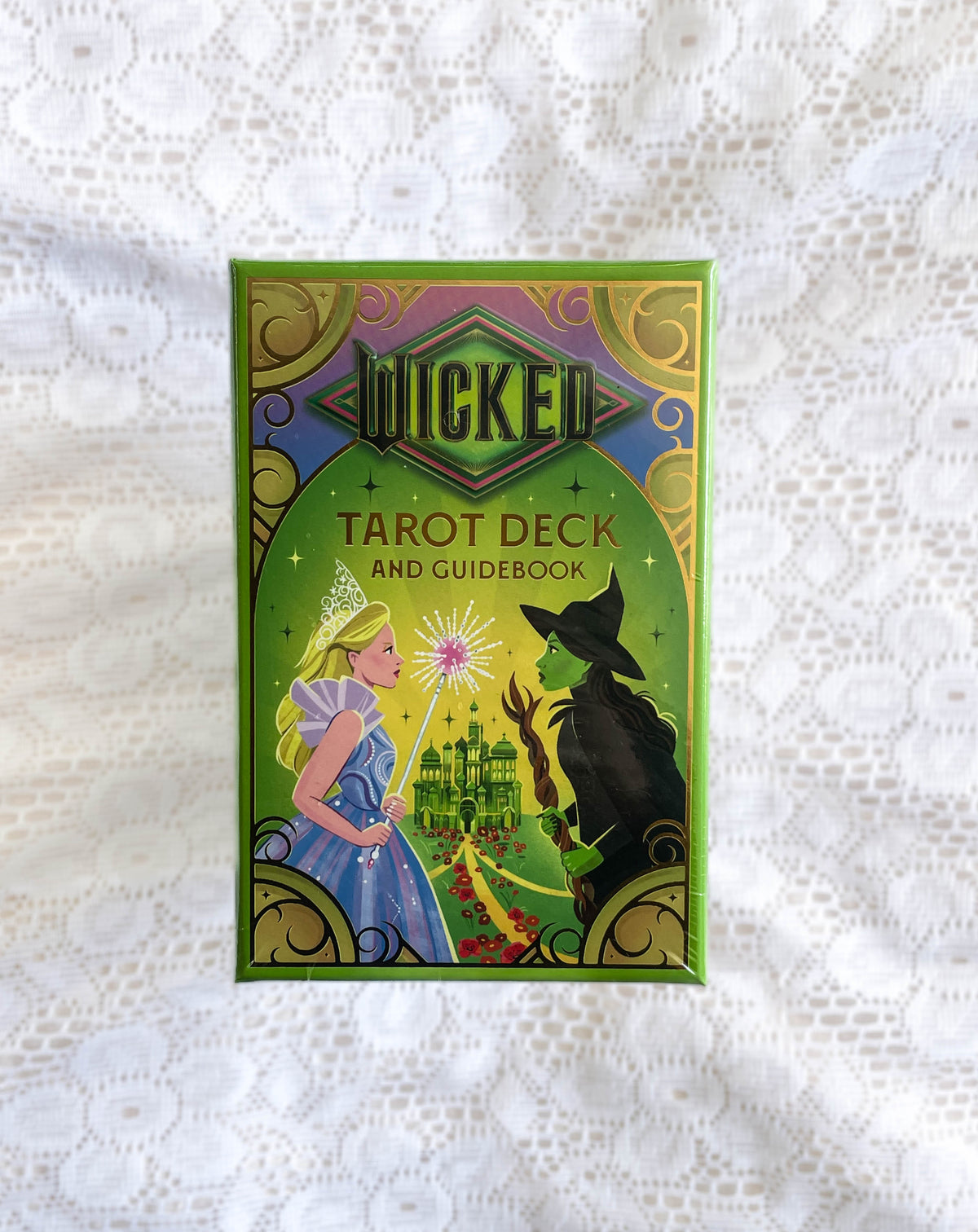 A green box labeled Wicked Tarot Deck by The Healing Hedge Witch features artwork of a blonde woman in blue and a green-skinned witch facing each other with a magical castle and sparkles between them.