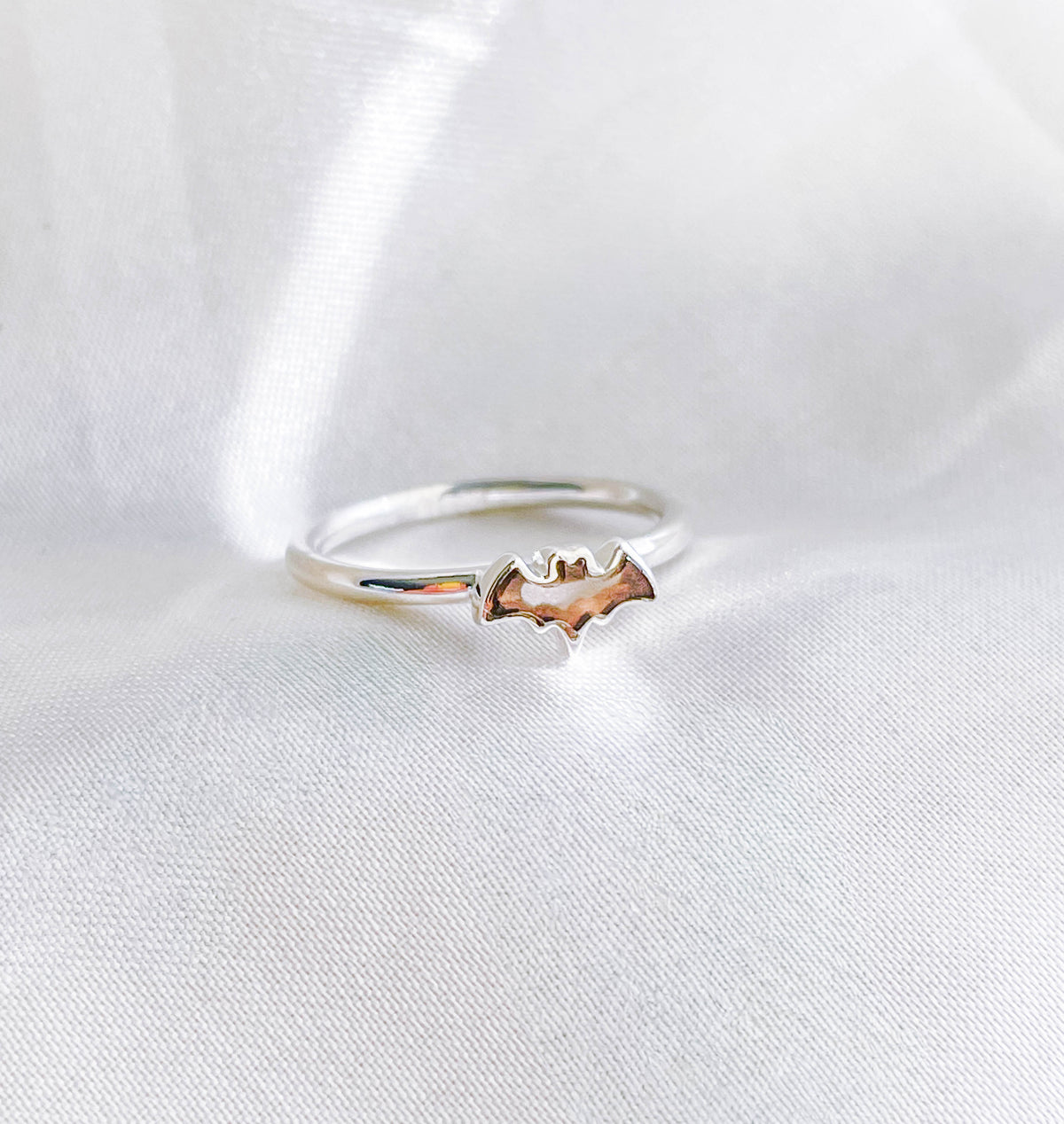 The Healing Hedge Witch Smoky Quartz Bat Crystal Stackable Ring features a small bat-shaped design, displayed on a soft white fabric background.