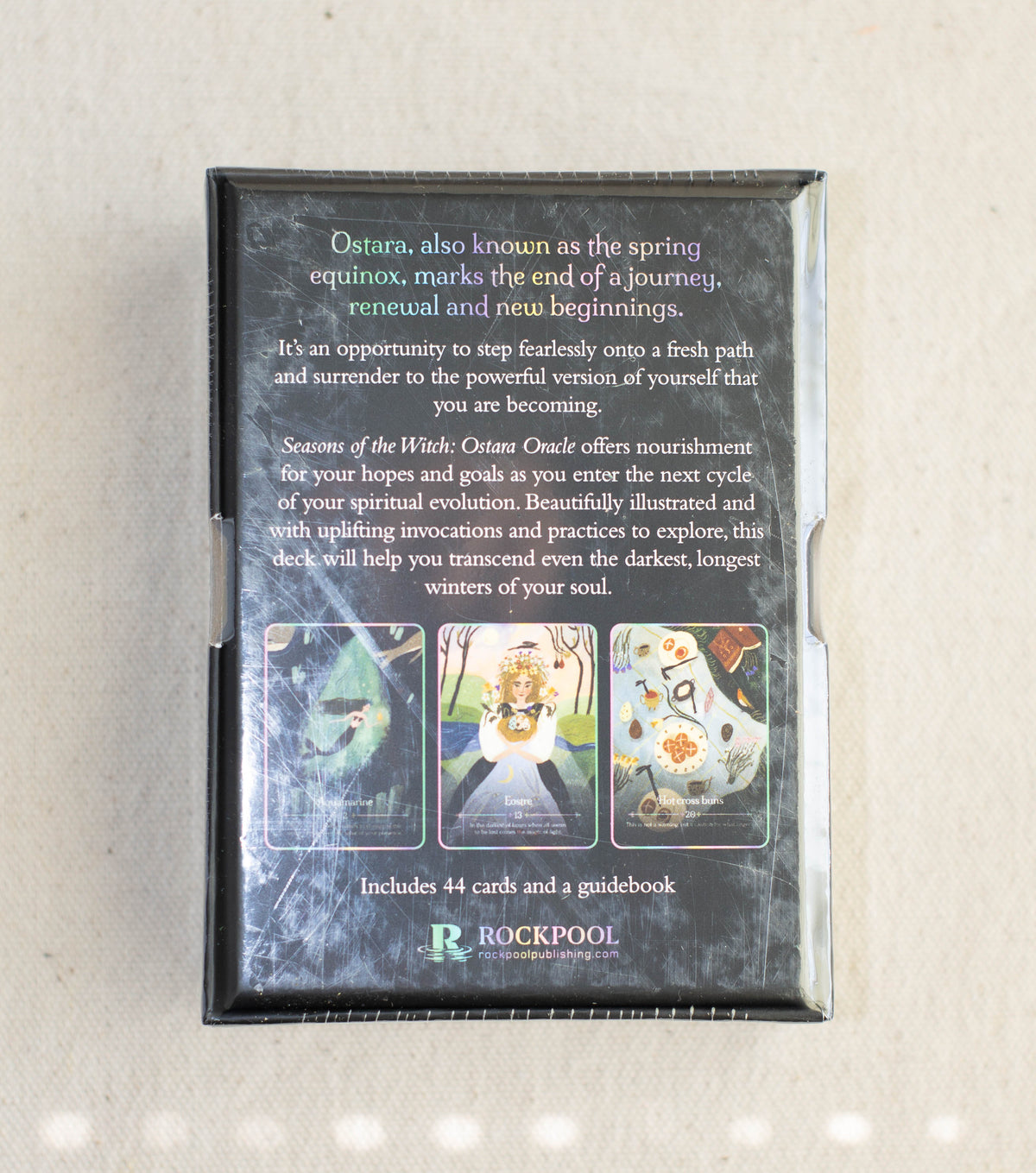 The back of the Seasons of the Witch Ostara Oracle deck box by The Healing Hedge Witch features renewal and spiritual growth text, three card samples, and a Rockpool logo, all set against a black background.