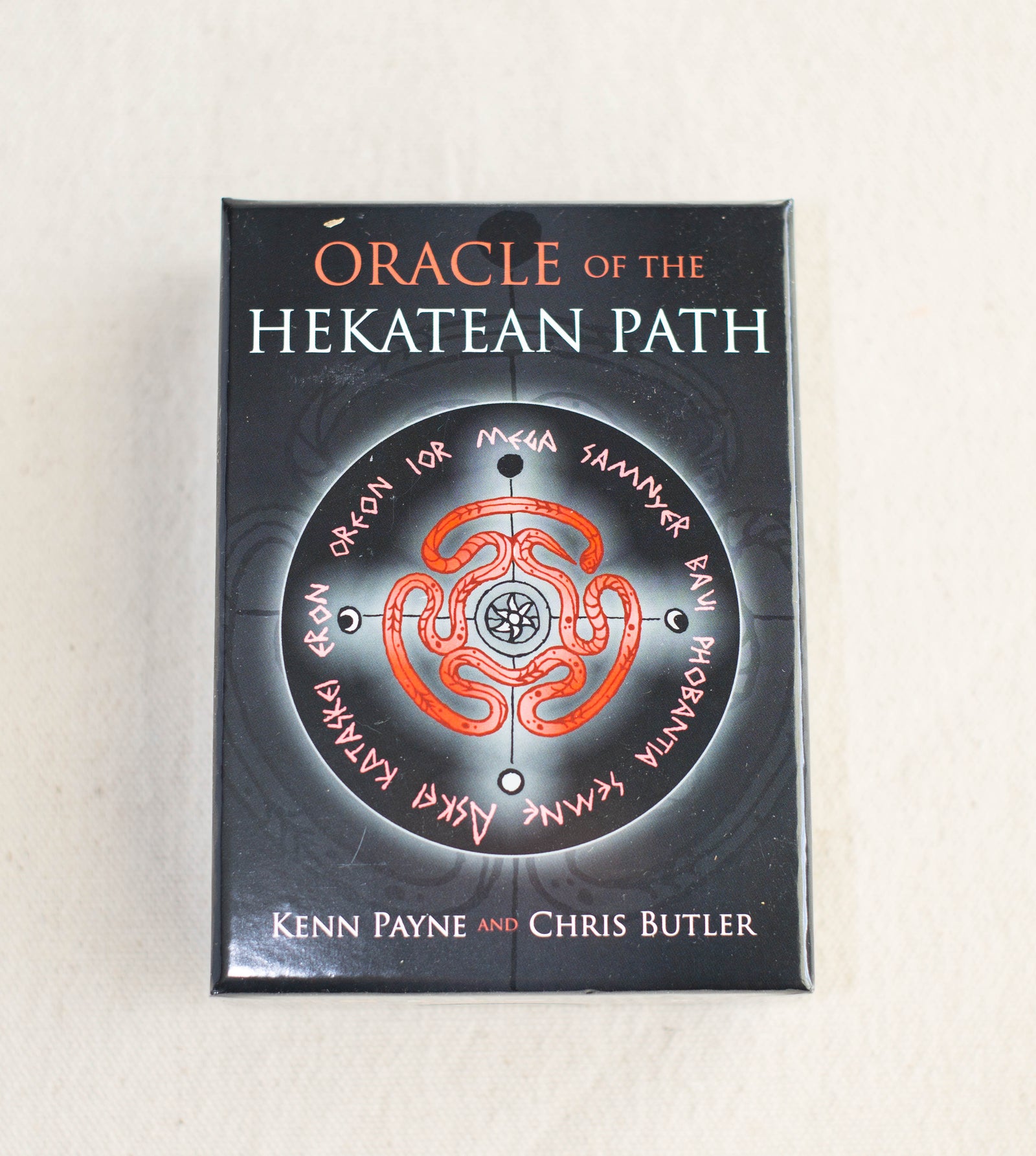 A box for Oracle of the Hekatean Path by The Healing Hedge Witch, featuring a circular red mystical design with runic symbols on a black background.