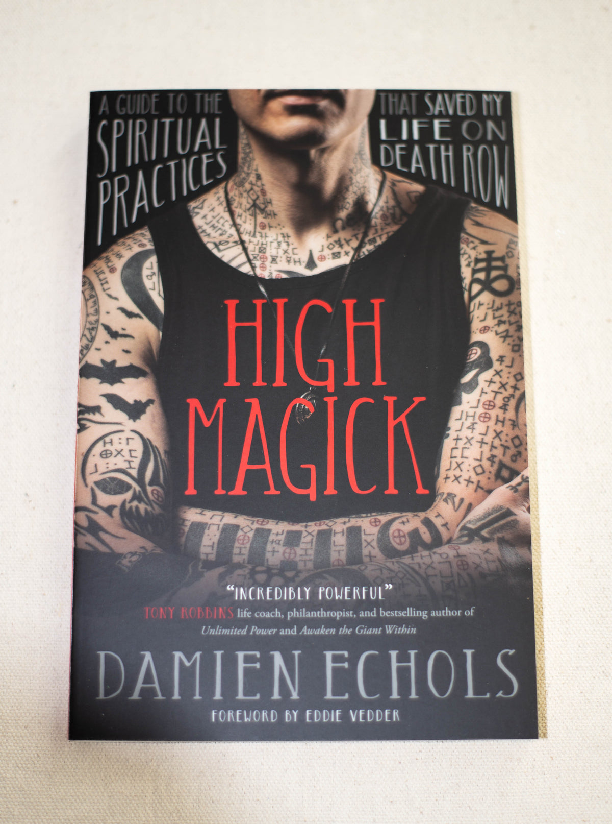 Book cover for High Magick by The Healing Hedge Witch features a tattooed person in a black tank top. Text: A guide to the spiritual practices that saved my life on death row. Foreword by Eddie Vedder.