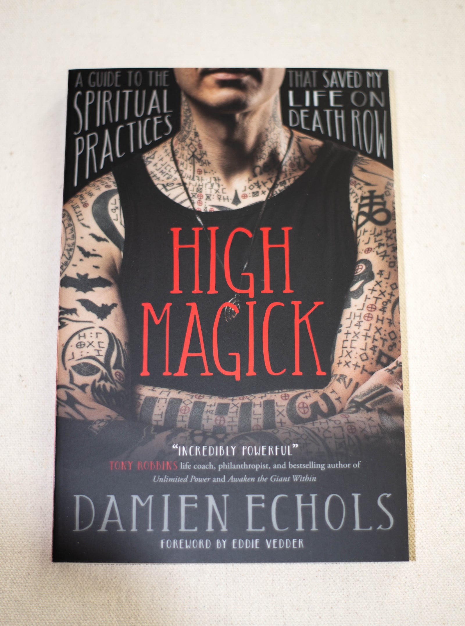 Book cover for High Magick by The Healing Hedge Witch features a tattooed person in a black tank top. Text: A guide to the spiritual practices that saved my life on death row. Foreword by Eddie Vedder.