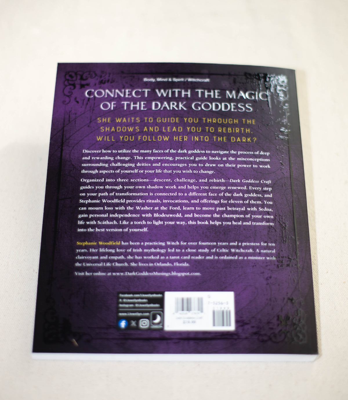 The back cover of Dark Goddess Craft by The Healing Hedge Witch has a purple background, decorative borders, and white text outlining the book’s theme and contents. Several logos and a website are shown at the bottom.