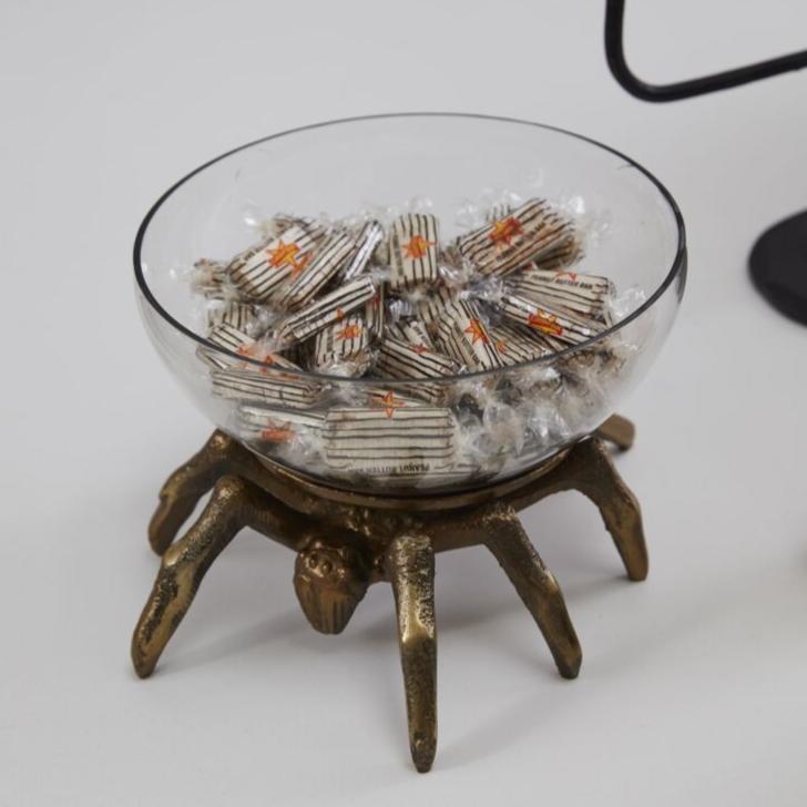 The Healing Hedge Witch's Arachnid Terrarium showcases striped candies atop a decorative brass stand—perfect for displaying creepy treasures in your Halloween setup.