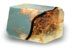 The T. S. Pink Corp SoapRocklet is a small rectangular bar with a marbled design, light blue exterior, and swirled brown and amber interior, inspired by gemstones.